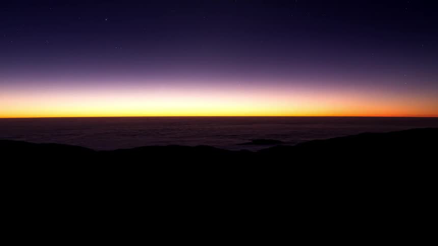 Time lapse of the sun setting over a sea of clouds in the mountains