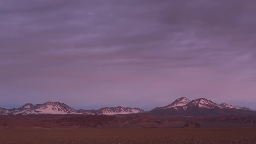 Time lapse of clouds changing color at sunset over a mountainous landscape