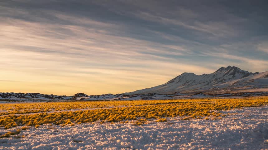 Landscape of mountains covered in snow and the sky turning purple and darkening