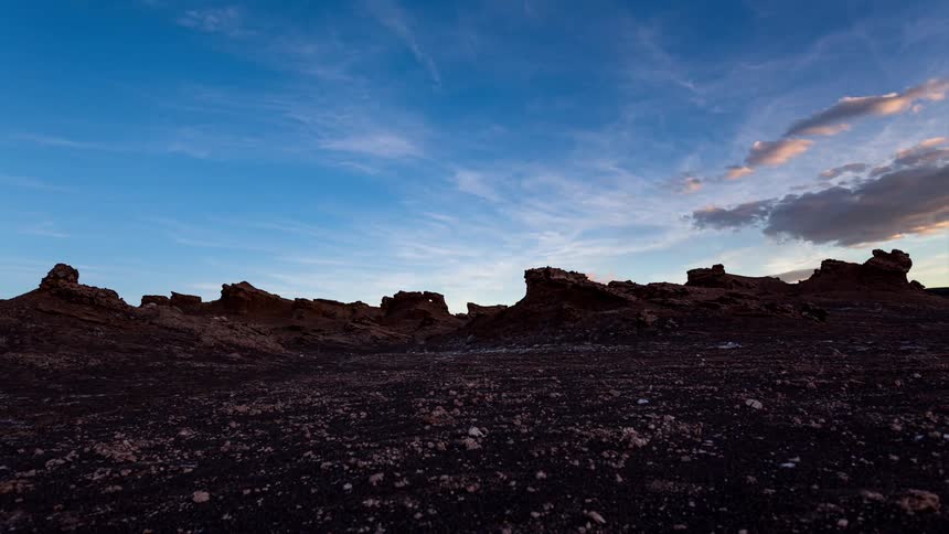Landscapes of rocks in a natural terrain against a sky that darkens in shades of purple