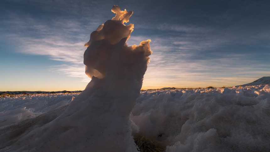 Tall natural ice formation on a frozen landscape from sunset to nighttime