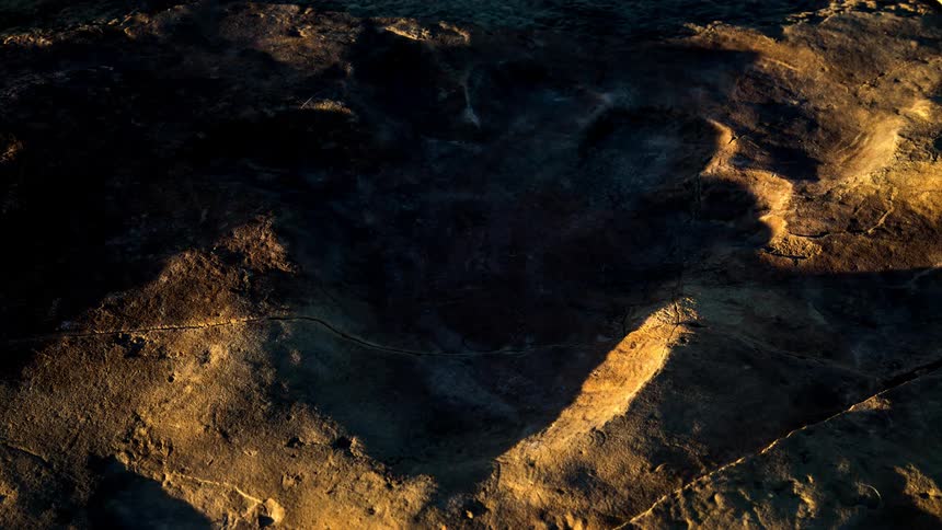 Shadows fill paw print shaped depression as day passes into night