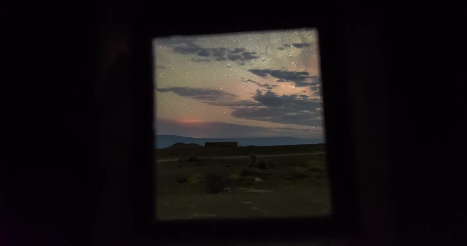 Time lapse of clouds rolling over a rural landscape under a starry night