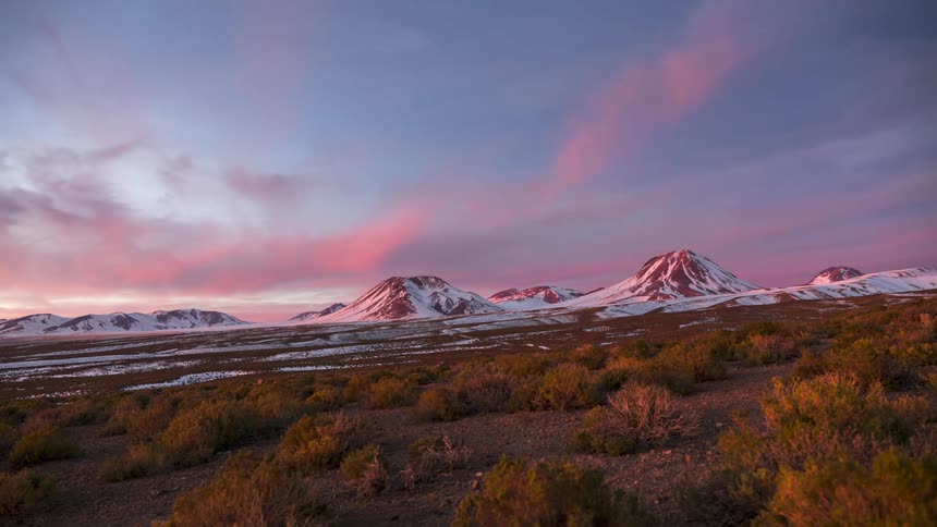 Snowy mountains against a red sky changing tones