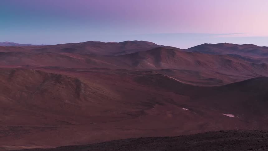 Shadows cover the mountains and puddles as the sun sets