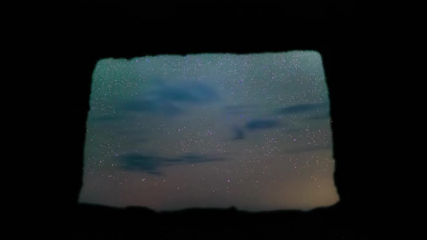 Wispy clouds speed across a night sky