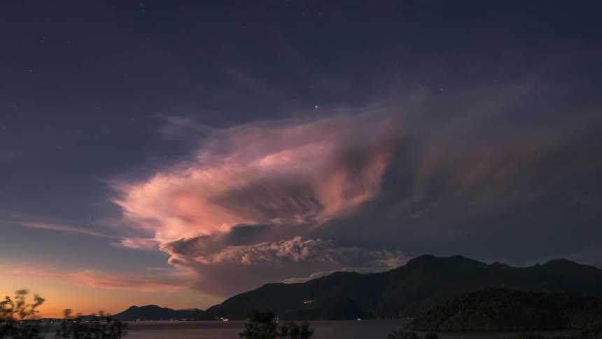 Cars are driving outdoors while a storm in the sky is brewing