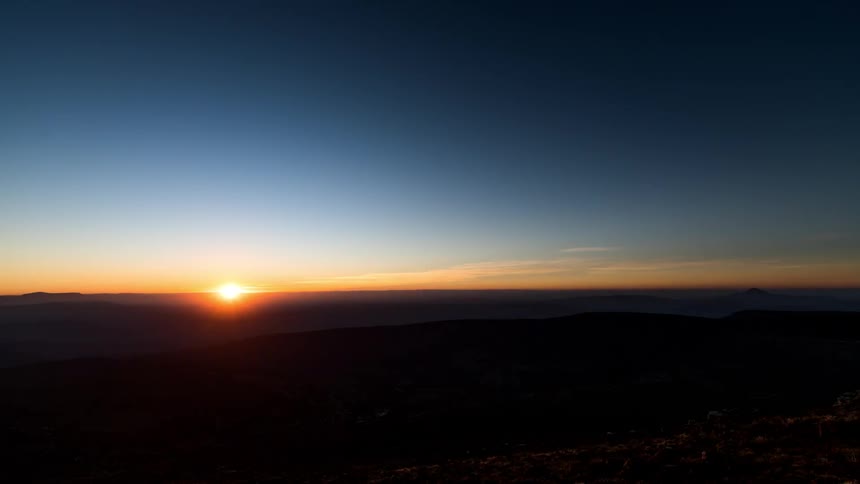 Time lapse of the sun setting over a mountainous landscape