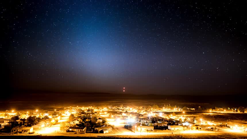 Time lapse of a starry night turning to sunrise over a small town