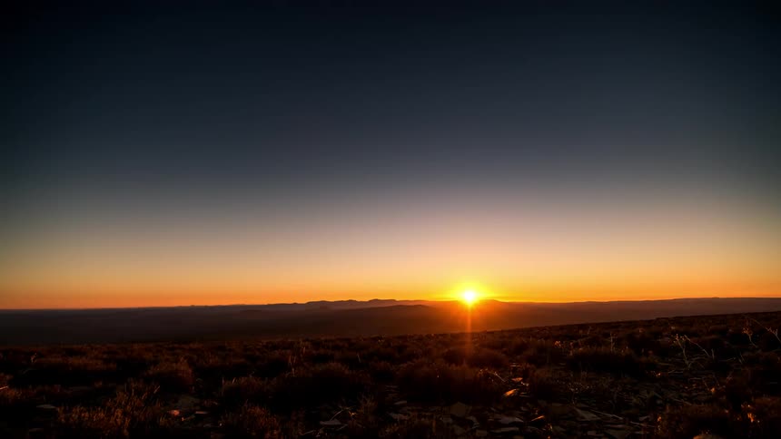 Time lapse of a starry night changing to daytime over a landscape