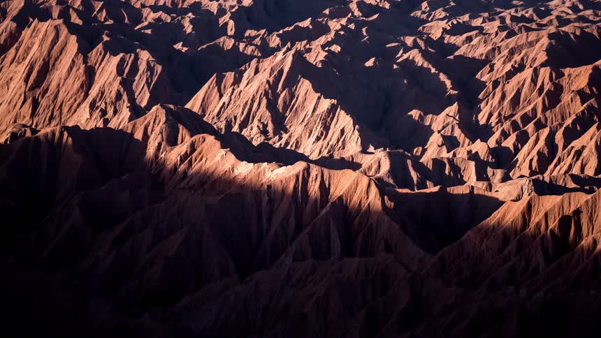 Time lapse of the changing colors of a jagged mountain range from daylight to night