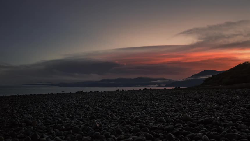 Time lapse of clouds rolling over a coastal area from night to sunrise
