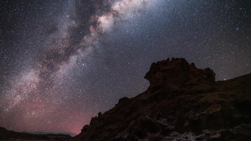 Upward view with the silhouette of mountains and a starry sky with the milky way
