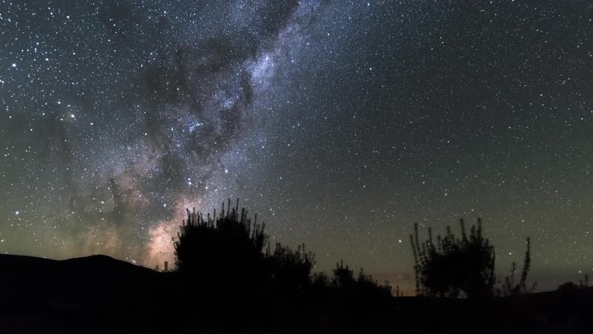 Time lapse of a starry night sky turning to sunset over a landscape