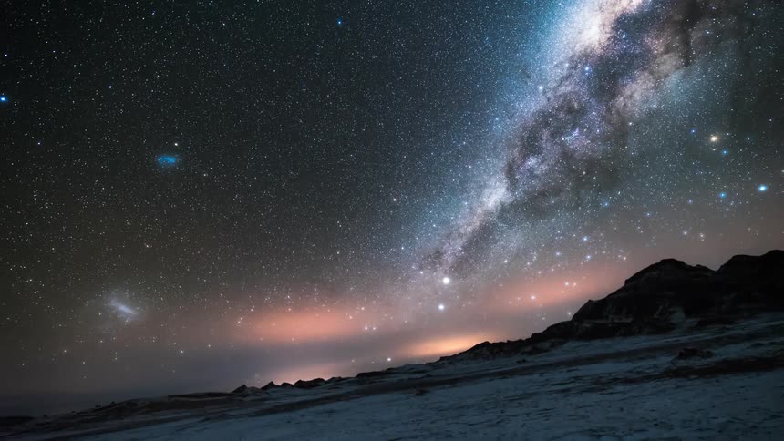 Starry night sky above snowy mountains