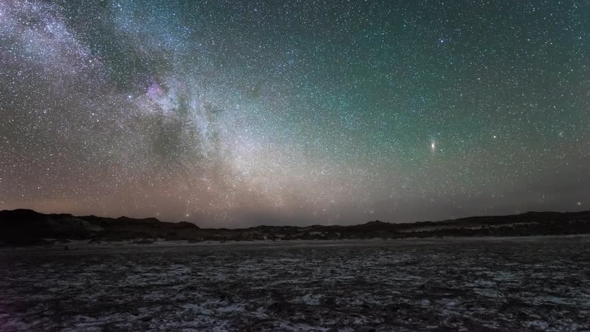 Snowy mountain scenery against a sky with the dawning milky way