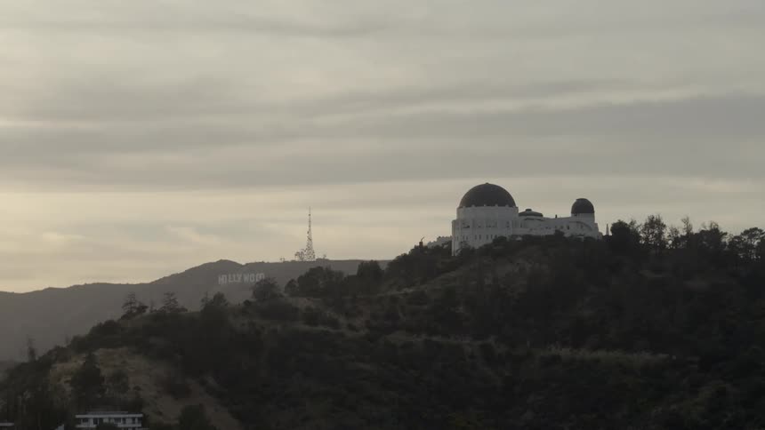 A domed structure sits on the top of a hill with hollywood spelled out on the side of a hill further back