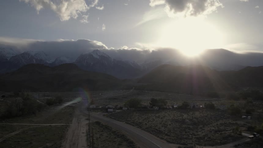 Aerial view of some country land  as seen while the sun sets behind the mountains