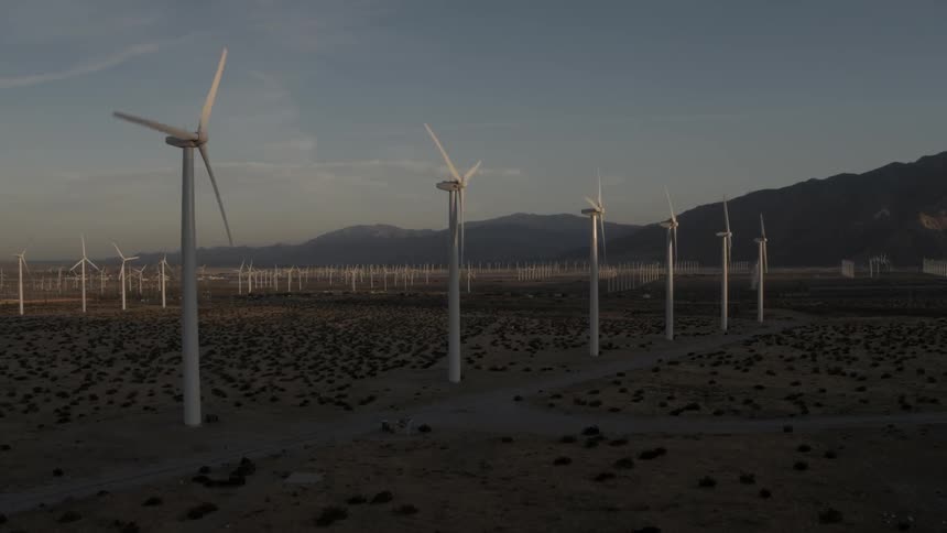 Wind turbines spin in a wind-farm in the desert at dawn
