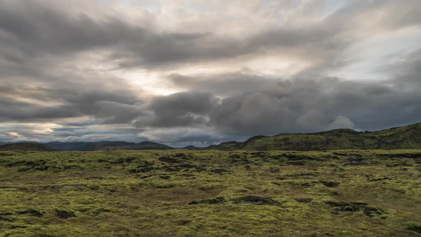 Landscape of greenish hills and mountains and dense clouds