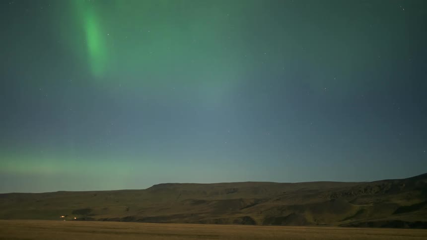 The green aurora moves over the hill