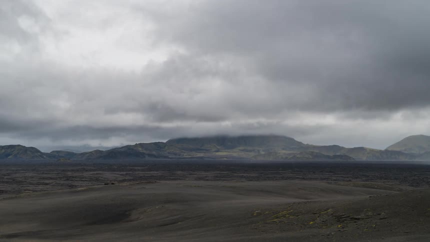 Time lapse of clouds rolling over a landscape with distant mountains