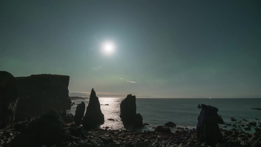 Ocean landscape with the rocky coast and the moon on the horizon