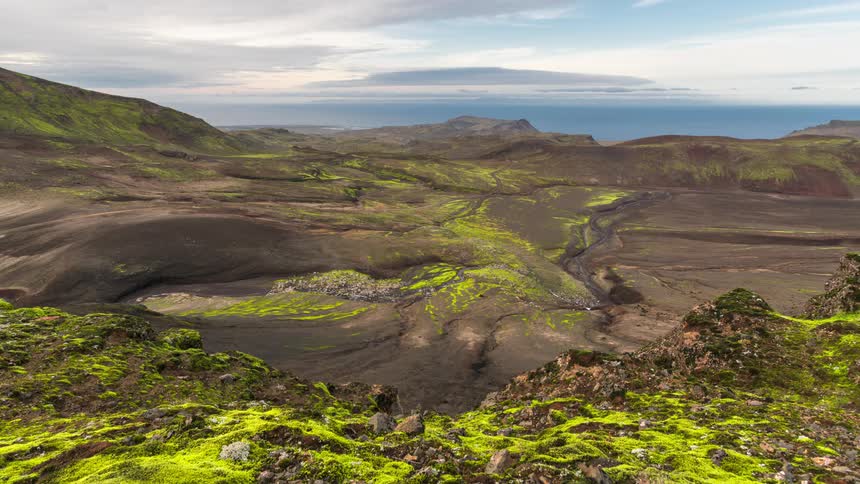 Landscape of a mountain valley with mosses against a partly cloudy sky