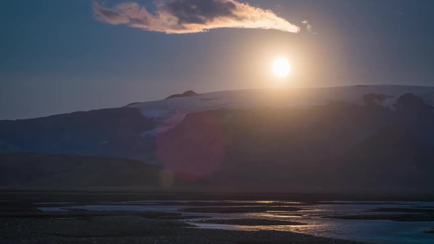 Time lapse of the sun rising over a snow capped mountain