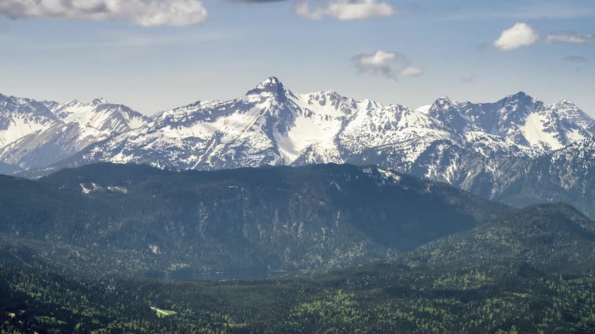 Landscape of green mountains with snowcapped peaks on the horizon