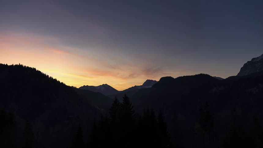Silhouette of mountains and trees with the sun rising on the horizon