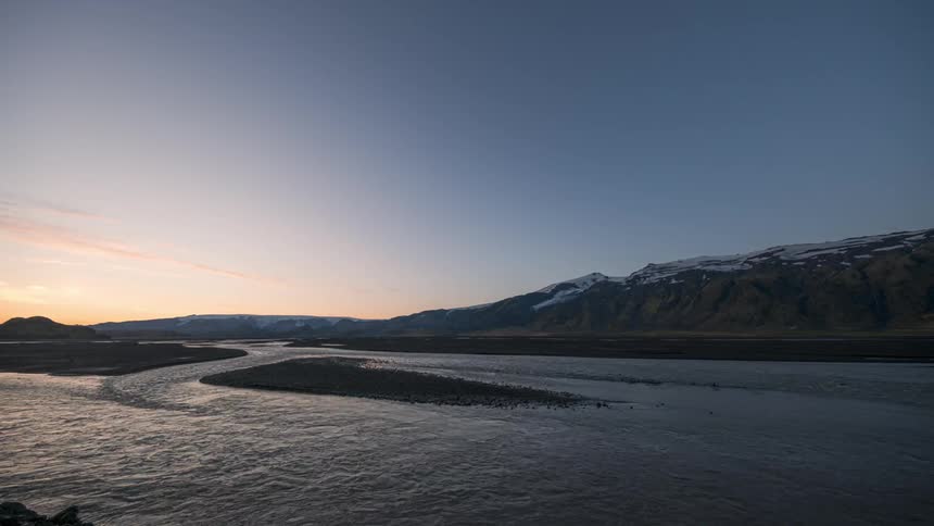 Landscape of mountains by a lake with a sun rising on the horizon