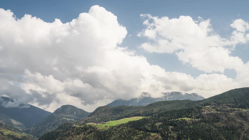 Time lapse of clouds rolling over the mountains uncer a blue sky