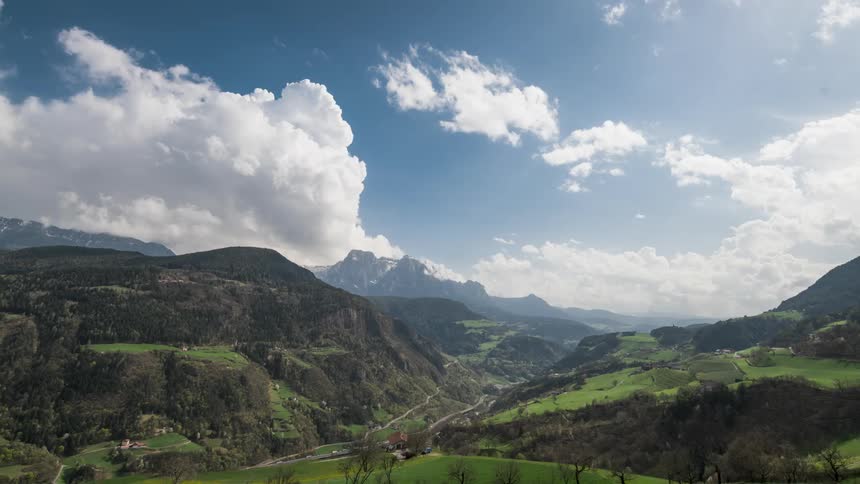 Time lapse of clouds rolling over a valley with green hills and fields