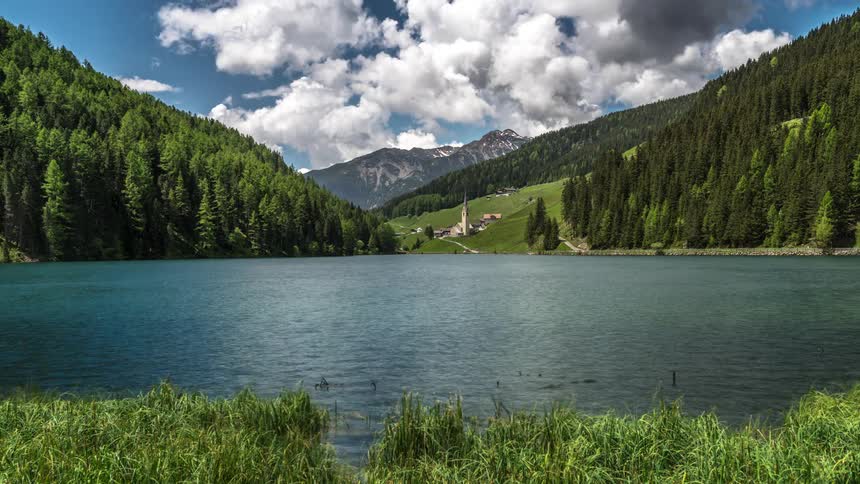 Mountainous landscape with greenish conifers on the edge of a lake on a cloudy day