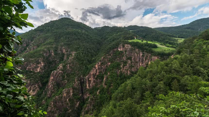 Natural landscape with a vast valley rocky slopes and dense vegetation under a partly cloudy sky