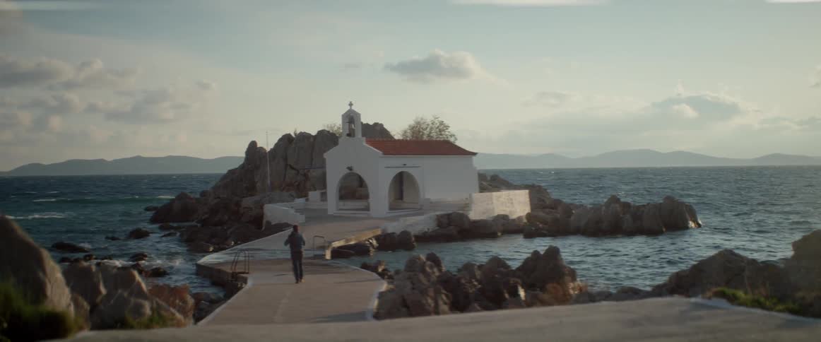 A man walks down a curving sidewalk to a church