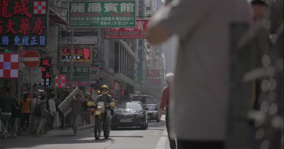 Pedestrians stand by as vehicles drive through a city street
