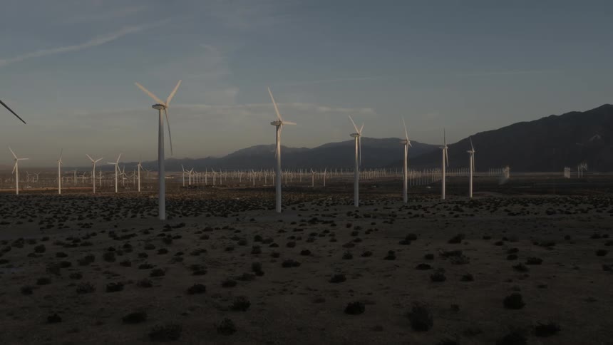 Rows of turbine blades turning on a wind farm