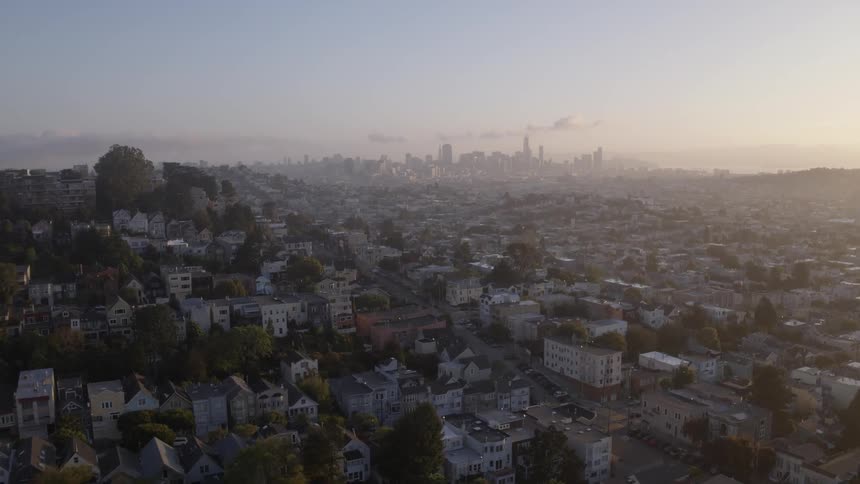 Aerial view of spread out suburbs with the large city's downtown in the distance at sunset