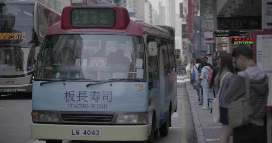 People get on a bus in a busy city and it departs