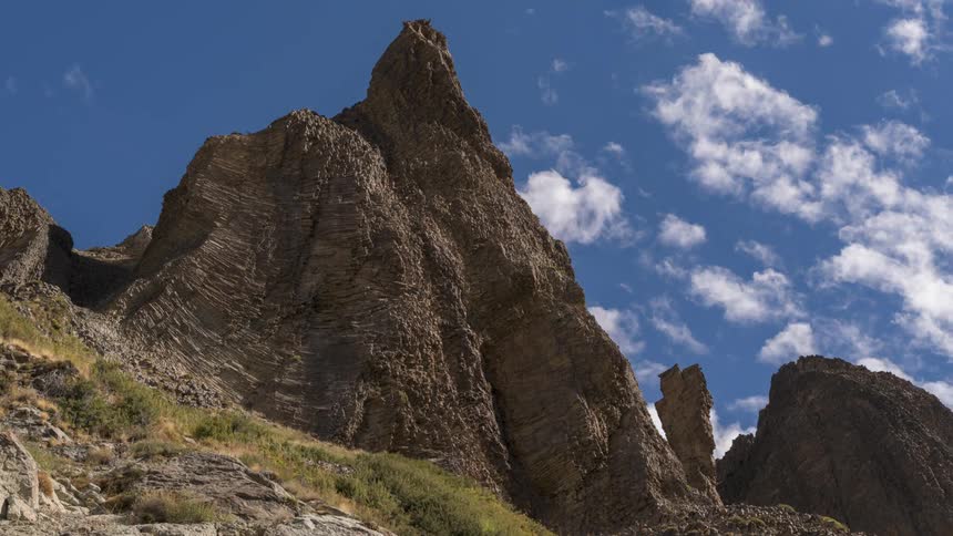 Cumulus clouds are moving above the rocky formation