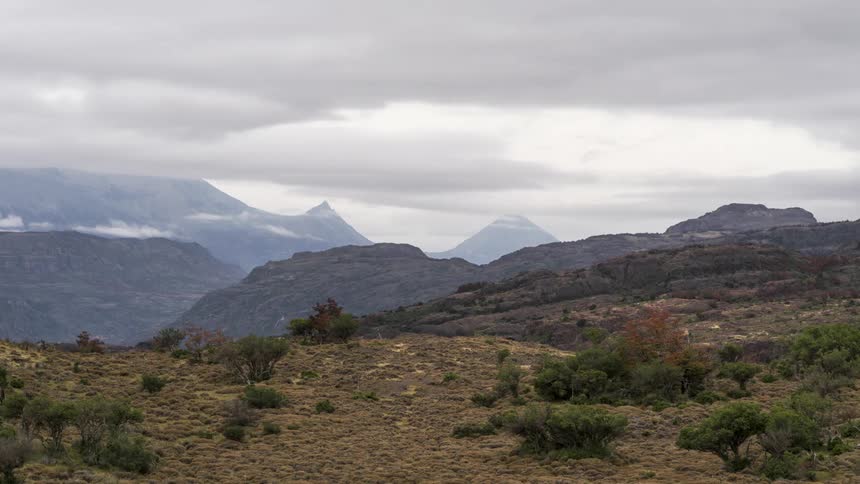 Time lapse of clouds rolling over a dry grassland with distant mountain peaks