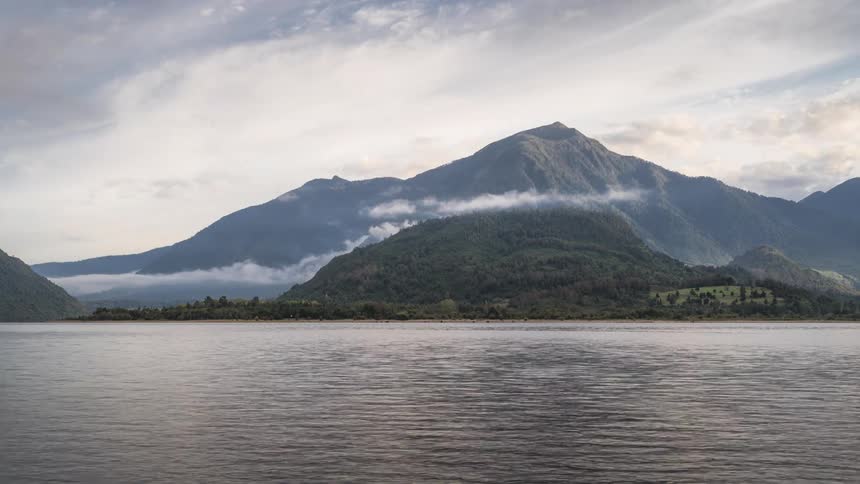 Scenery of green mountains on the edge of a lake on a partially cloudy day