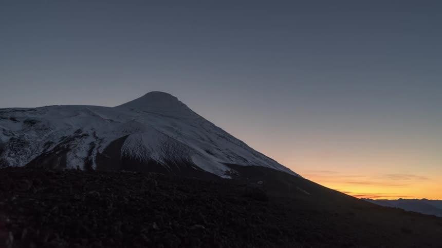 The sun is rising above the snow covered mountains