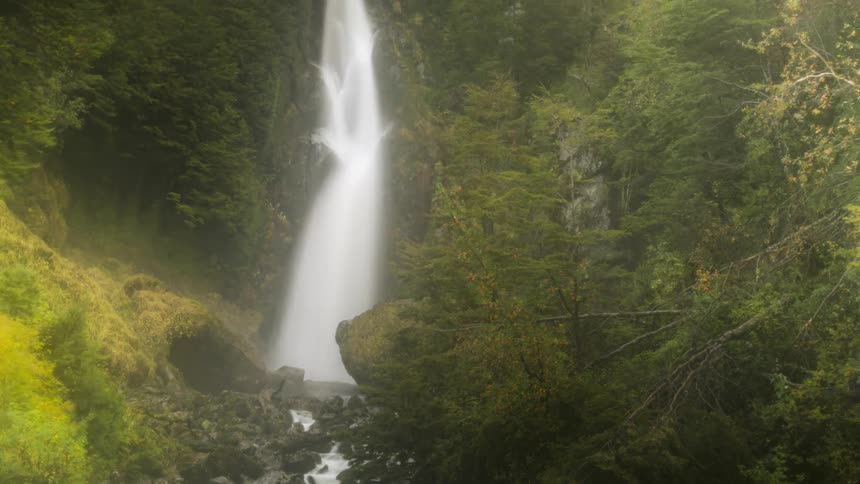 A waterfall is flowing into the rocky river during spring season