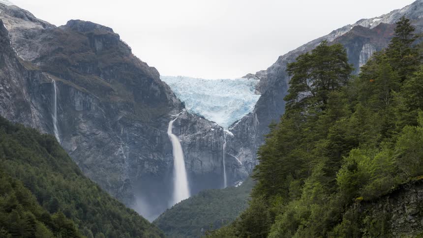 A waterfall is flowing between the mountain range in spring