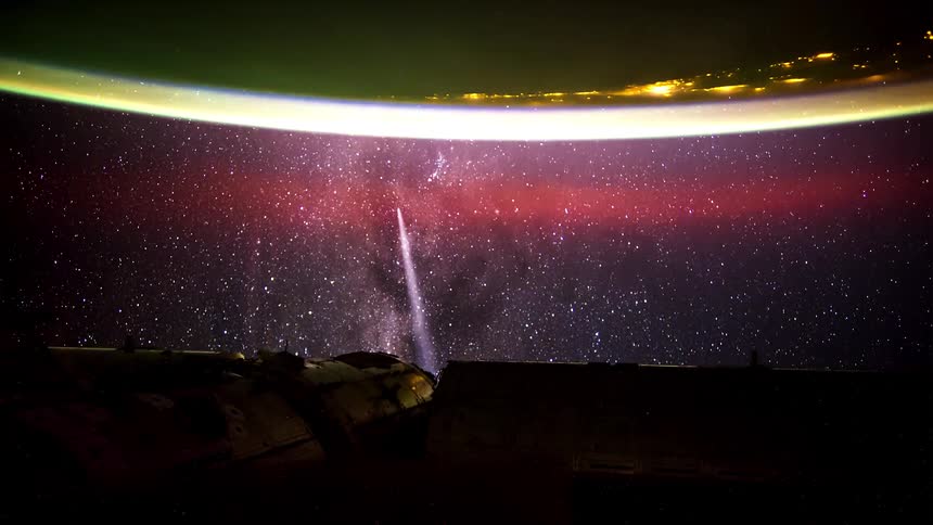Space station orbits night side of earth passing over city lights contrasting with the dark