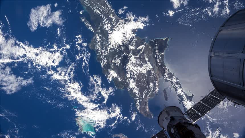 View of earth from a space antenna highlighting a group of islands surrounded by blue waters and white clouds