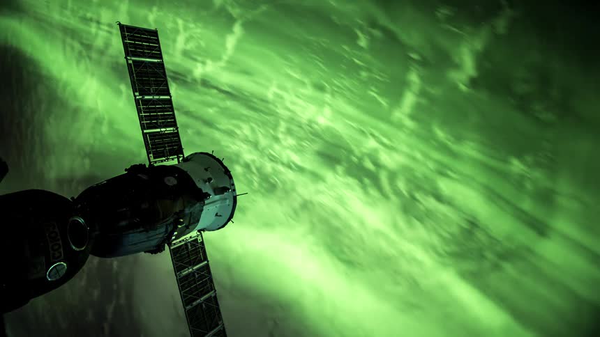 Part of a spaceship with large solar panels contrasting with the natural phenomenon of the northern lights in the background